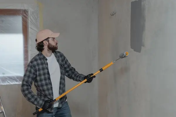 Painter rolling grey paint onto an interior wall in Savannah