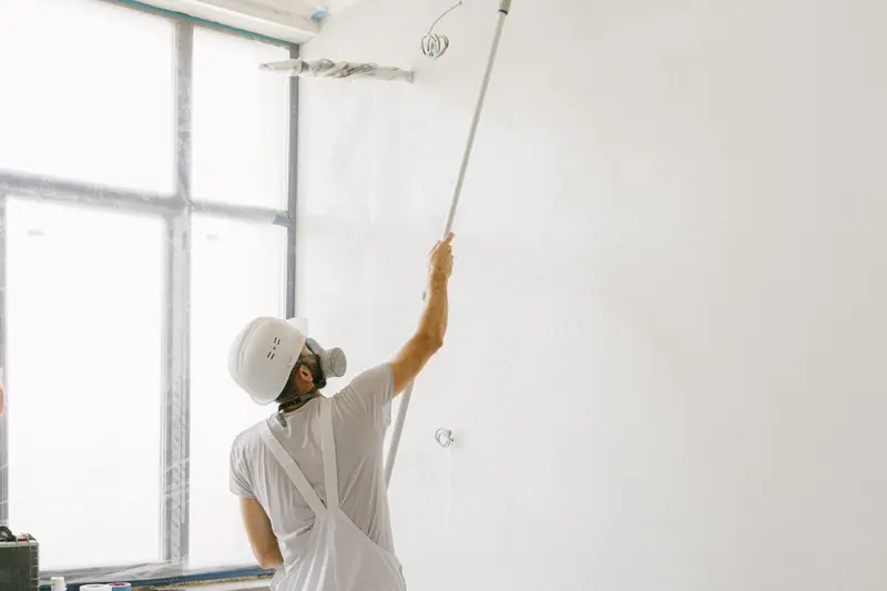 Interior painting in Savannah: professional painter in whites rolling paint onto a wall